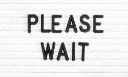 Black color letter in word please wait on white felt board background Black color letter in word please wait on white felt board background